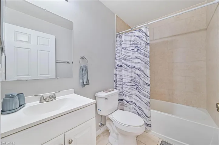 Full bathroom featuring toilet, shower / bath combo, vanity, and tile patterned flooring