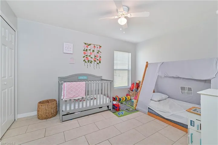 Tiled bedroom with a closet, a nursery area, and ceiling fan