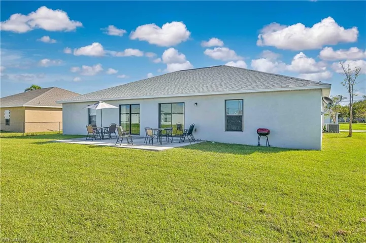 Back of property with central AC, a yard, and a patio