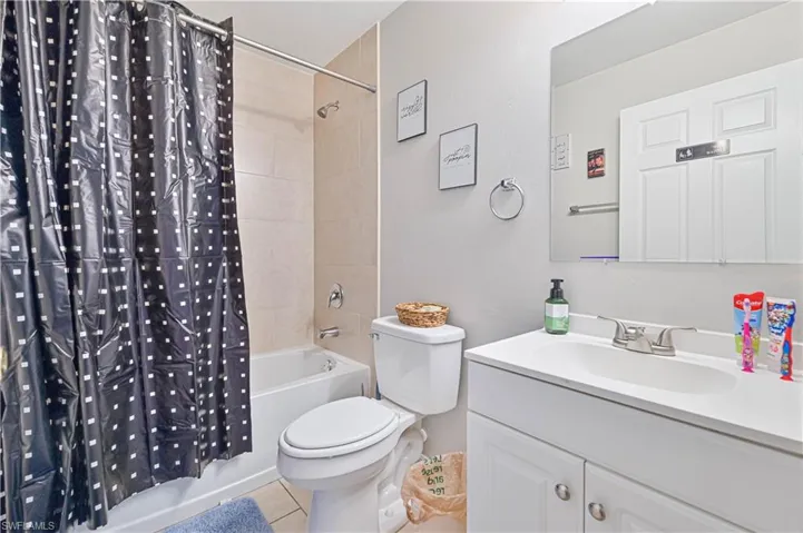 Full bathroom featuring vanity, shower / bath combination with curtain, toilet, and tile patterned floors