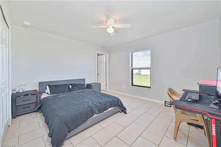 Bedroom with a closet, light tile patterned floors, and ceiling fan