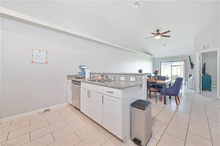 Kitchen featuring light stone countertops, dishwasher, white cabinets, and light tile patterned floors