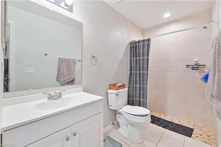 Bathroom featuring vanity, toilet, a shower with curtain, and tile patterned flooring