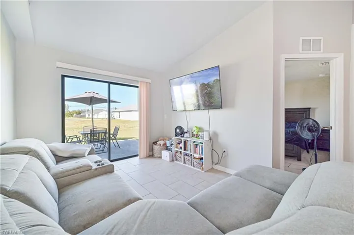 Living room featuring light tile patterned floors and vaulted ceiling