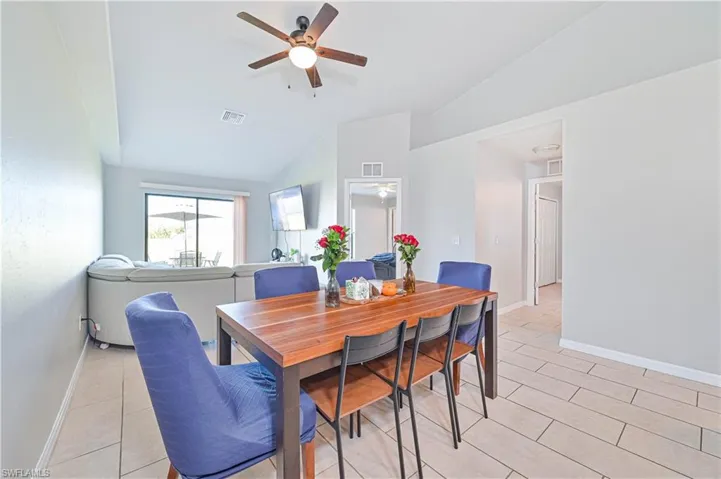 Dining area featuring ceiling fan, light tile patterned flooring, and vaulted ceiling