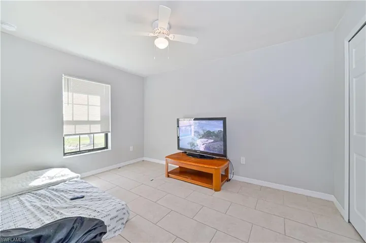 Tiled bedroom featuring ceiling fan
