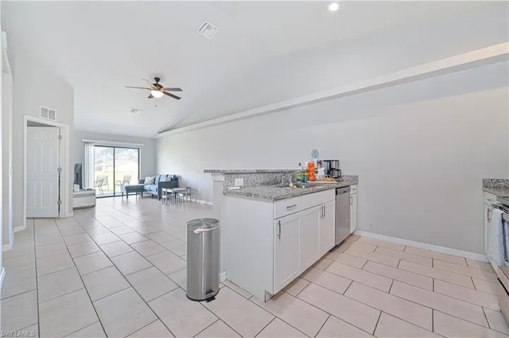 Kitchen with white cabinetry, ceiling fan, light tile patterned flooring, and stainless steel dishwasher