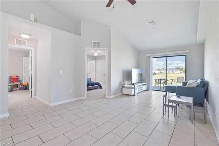 Tiled living room with ceiling fan and high vaulted ceiling