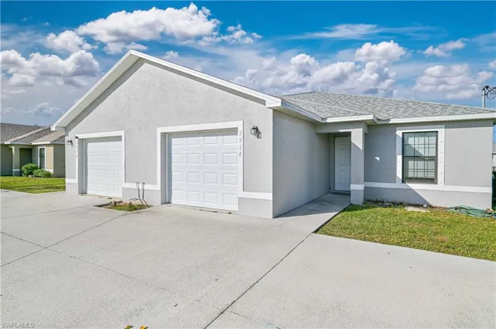 Ranch-style home featuring a garage and a front lawn
