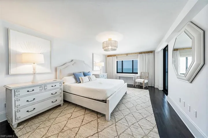 Generously sized primary bedroom with custom window treatments and sliding doors to the balcony