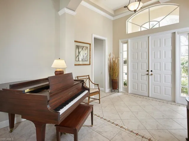 Large foyer entry with double front doors, soaring ceiling, custom neutral color ceramic tile floor