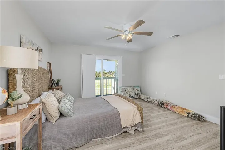 Bedroom featuring access to outside, wood finished floors, visible vents, and ceiling fan