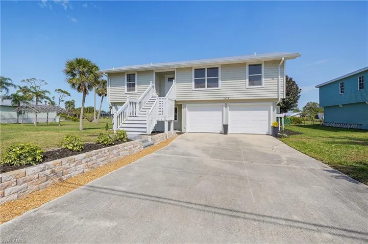 View of front of property featuring a front yard, an attached garage, and driveway