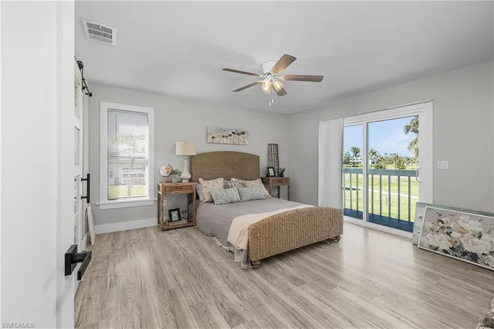 Bedroom featuring visible vents, light wood-type flooring, a barn door, and access to outside