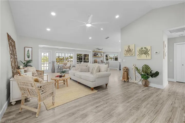 Living area with recessed lighting, baseboards, light wood-type flooring, and high vaulted ceiling