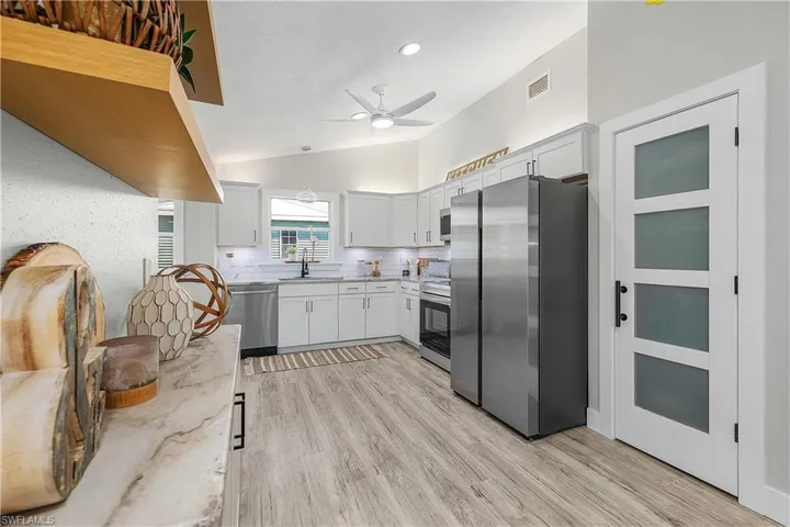 Kitchen with light stone countertops, visible vents, lofted ceiling, stainless steel appliances, and decorative backsplash