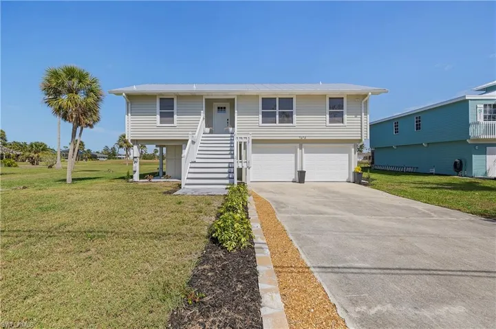 View of front facade with a front yard, stairway, an attached garage, and driveway