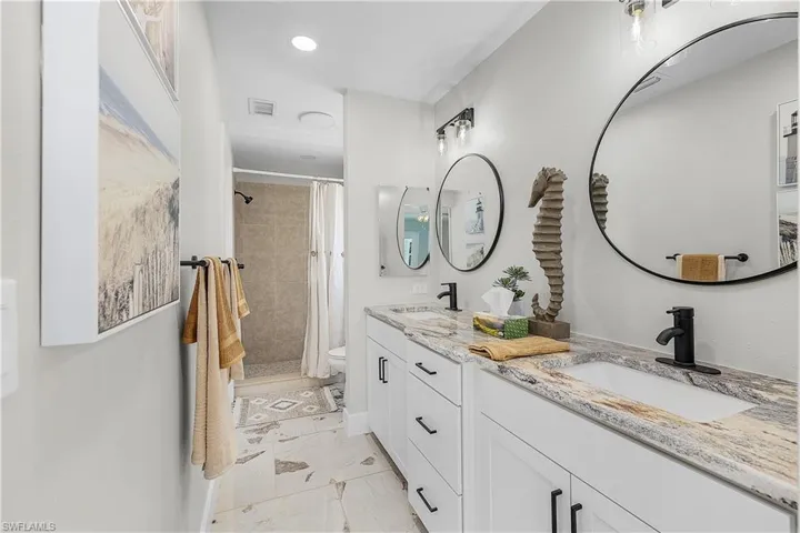 Full bath featuring visible vents, marble finish floor, tiled shower, and a sink