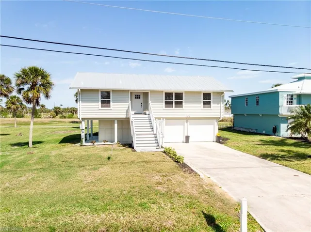 View of front of house with stairs, a front lawn, a garage, and driveway