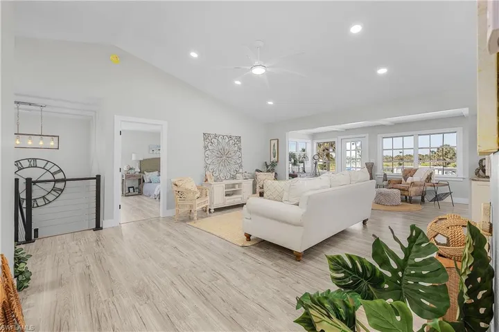 Living area featuring recessed lighting, baseboards, wood finished floors, and ceiling fan with notable chandelier