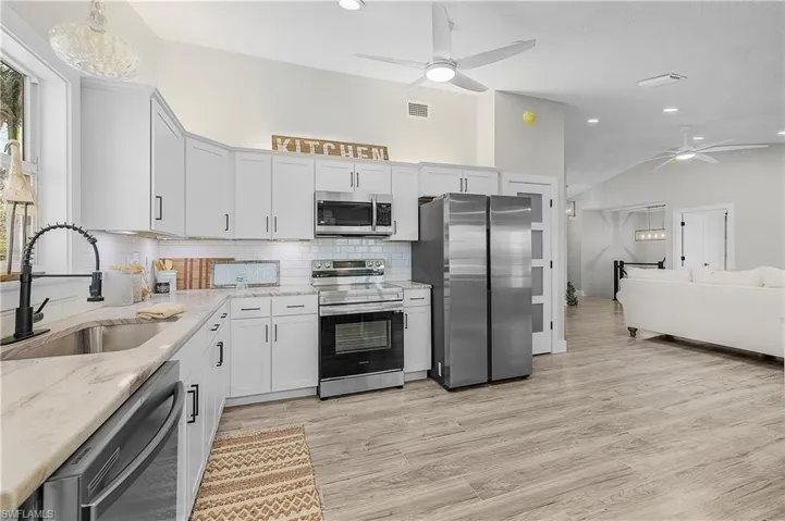 Kitchen with a sink, light stone counters, tasteful backsplash, stainless steel appliances, and light wood-style floors