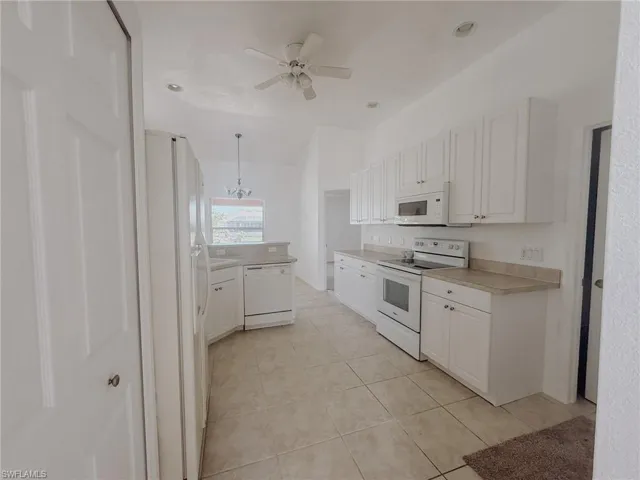 Kitchen featuring light tile patterned floors, light countertops, ceiling fan, white appliances, and white cabinetry