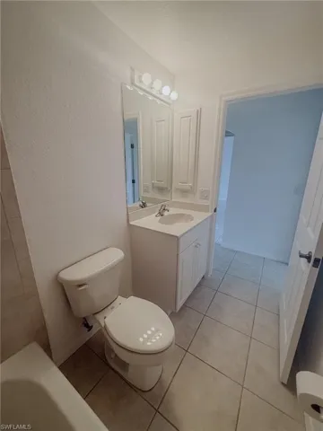 Bathroom with a bathing tub, toilet, tile patterned flooring, and vanity