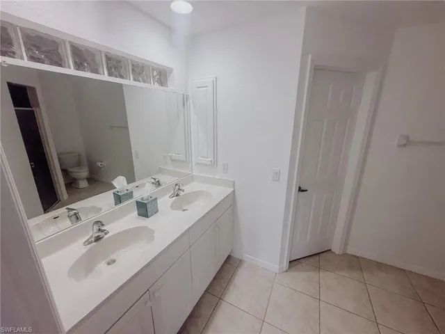 Bathroom featuring toilet, double vanity, and a sink
