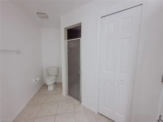 Full bathroom with a stall shower, a closet, visible vents, toilet, and tile patterned floors