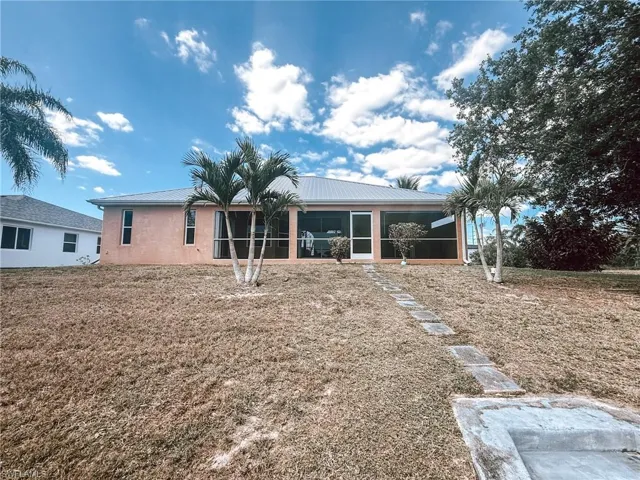 Back of house with a yard, metal roof, patio, and stucco siding