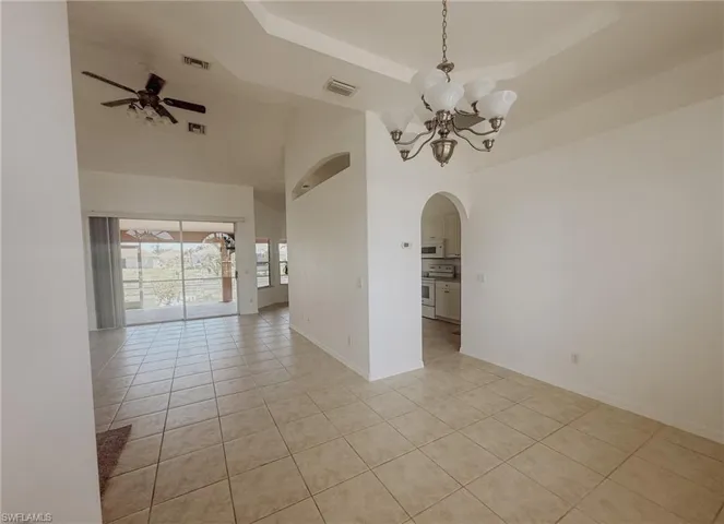 Spare room with arched walkways, light tile patterned floors, and visible vents