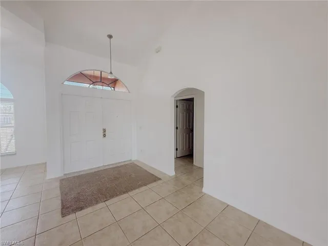 Foyer entrance featuring arched walkways, high vaulted ceiling, and light tile patterned floors