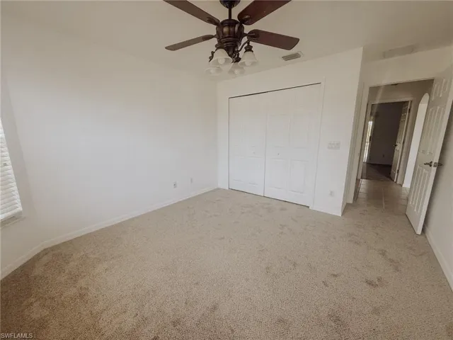 Unfurnished bedroom featuring visible vents, baseboards, a closet, and light carpet