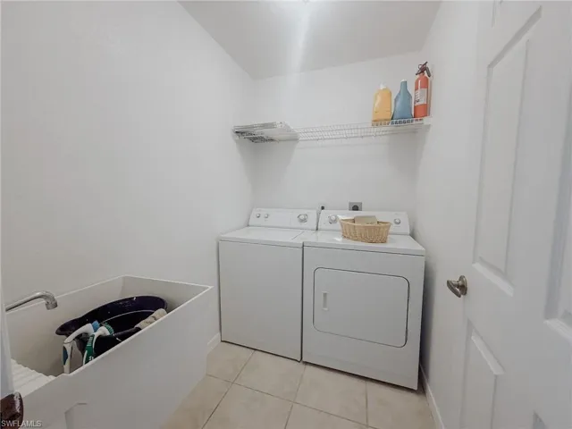 Washroom featuring laundry area, light tile patterned floors, baseboards, and washing machine and dryer