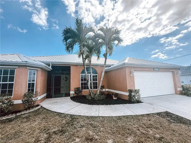 Ranch-style home with driveway, metal roof, a garage, stucco siding, and screened in front porch