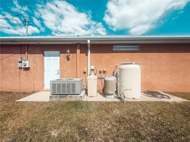 Rear view of house featuring a yard, stucco siding, and central air condition unit