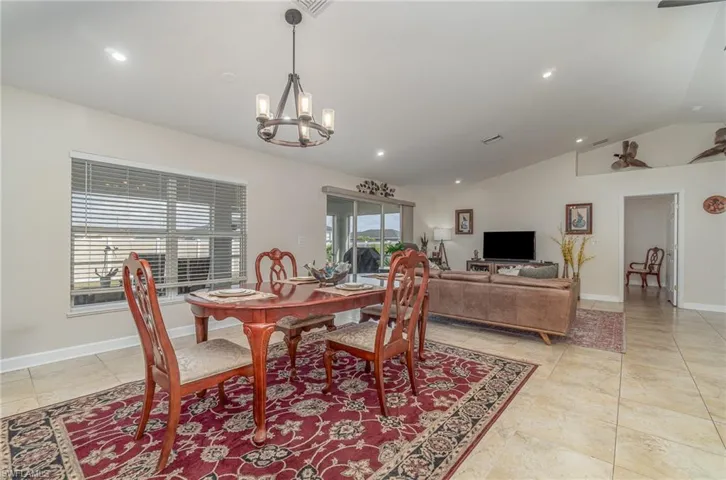 Dining area featuring light tile patterned floors, vaulted ceiling, and a chandelier