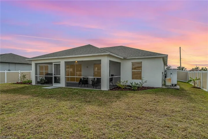 Back house at dusk featuring a yard and lanai