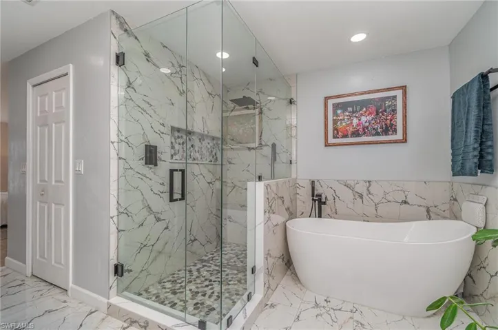 Bathroom featuring independent shower and bath and tile walls