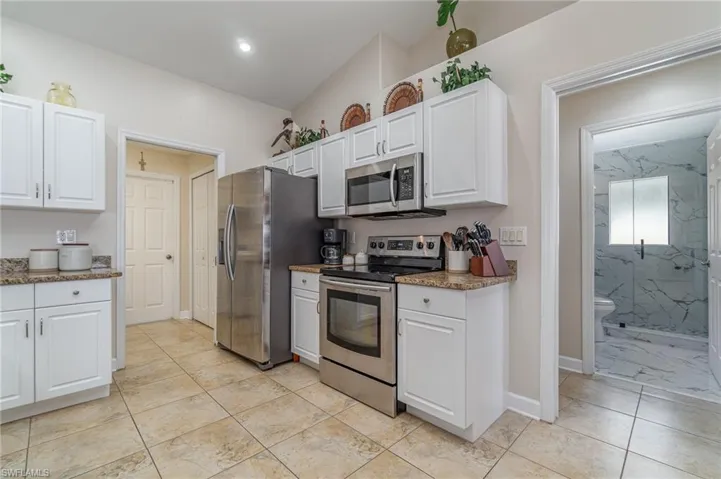 Kitchen featuring stainless steel appliances, dark stone countertops, and white cabinets
