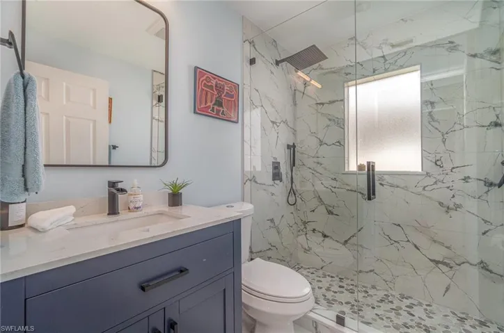 Bathroom featuring toilet, vanity, and an enclosed shower