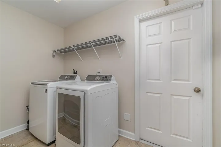 Laundry room with light tile patterned floors and washer and clothes dryer