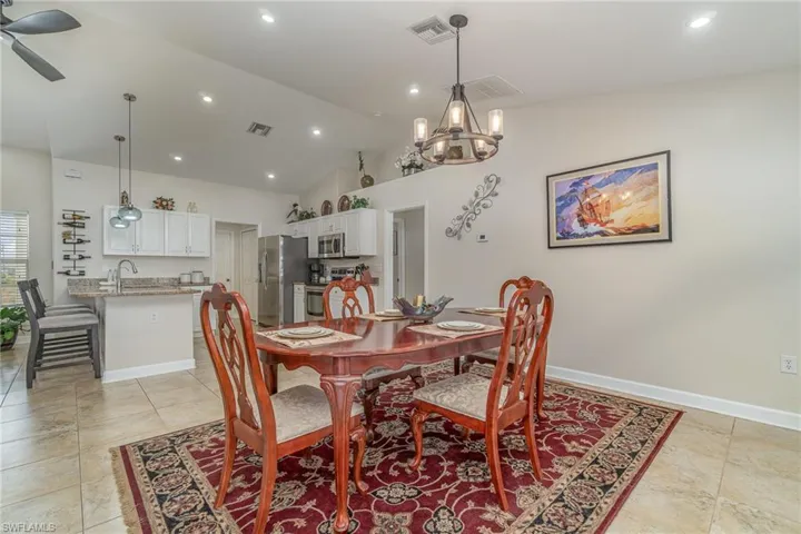 Dining area featuring ceiling fan with notable chandelier and high vaulted ceiling