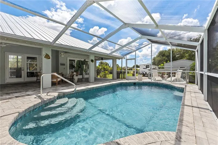 View of pool with french doors, a lanai, a patio area, and ceiling fan