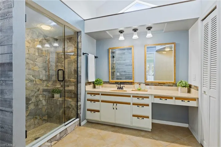 Bathroom with vanity, tile patterned flooring, and a shower with door