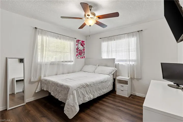 Bedroom with dark wood-type flooring, ceiling fan, and a textured ceiling