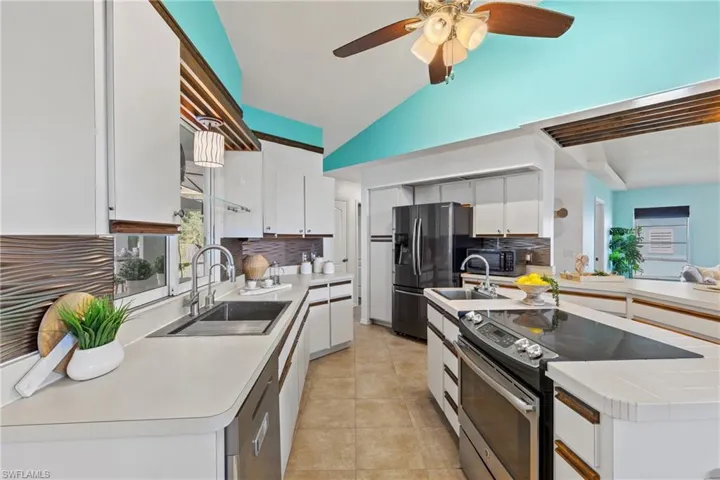 Kitchen with white cabinets, stainless steel appliances, sink, ceiling fan, and tasteful backsplash