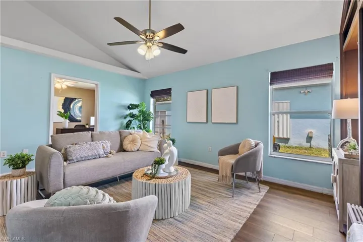 Living room with ceiling fan, wood-type flooring, and vaulted ceiling