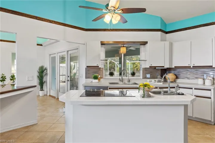 Kitchen featuring white cabinets, ceiling fan, and tile counters