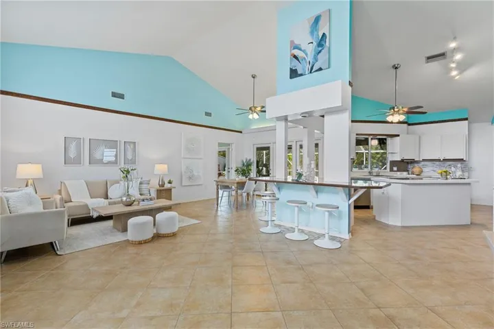 Kitchen featuring a breakfast bar, ceiling fan, white cabinets, and tasteful backsplash
